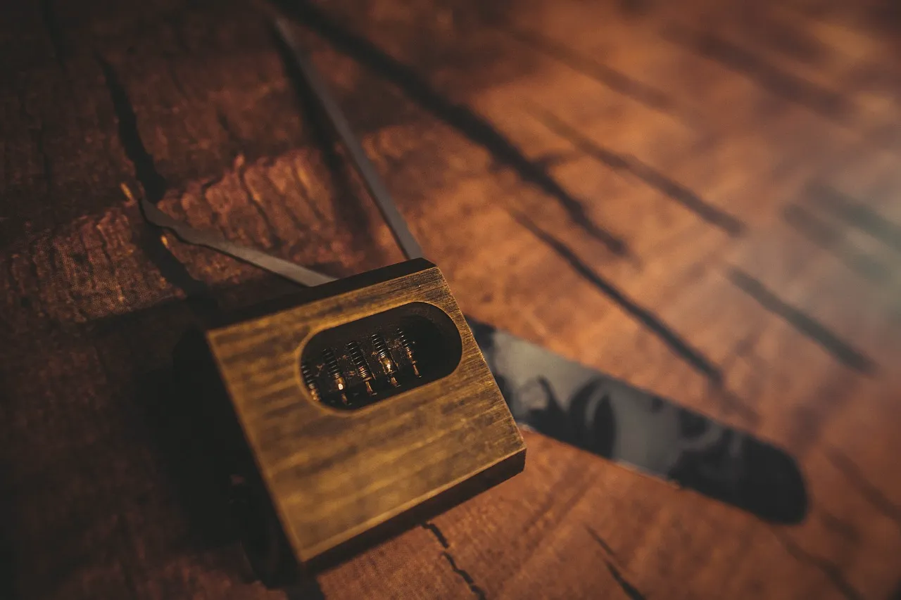 A close-up of a rustic brass combination lock and lockpick tools on a textured wooden surface.